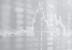 Blurred financial charts and data overlays showing stock prices and line graphs, conveying financial market analysis in progress.