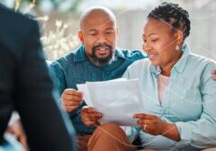 Couple reviewing documents with a financial advisor during a consultation at home or office.